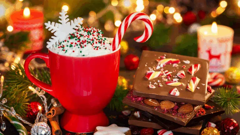 A bright cup of hot cocoa with a candy cane and some peppermint bark