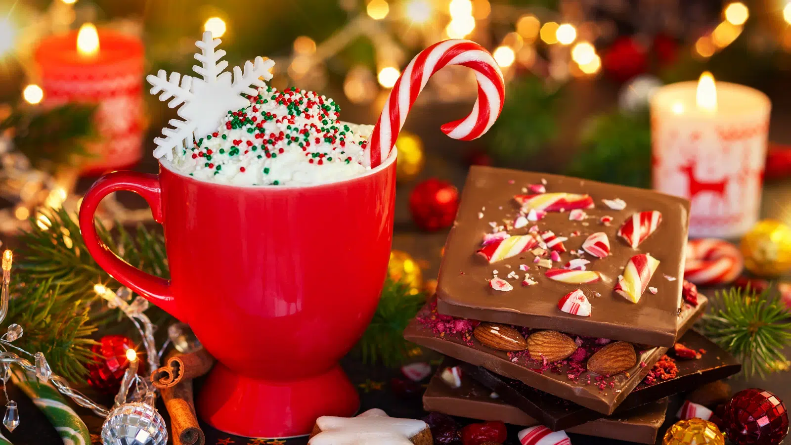 A bright cup of hot cocoa with a candy cane and some peppermint bark