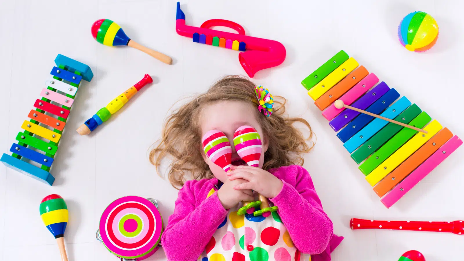 A little girl surrounded by colorful toy instruments