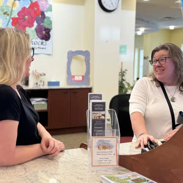 Two staff members having a conversation at the library circulation desk
